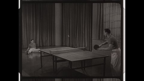 1950s Colorado Springs, CO. Two Men play Table Tennis or Ping Pong in front of Large Curtain. The sequence includes Slow Motion Paddle Hits. 4K Overscan of Vintage Archival 16mm Film Print. 