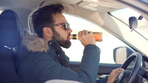Drunken Driving Risk Car Accident.Man Holding Alcohol Bottle In Car. Dangerous On Road Drunk Driver.Stress Unlawful Intoxicated Drive Auto.Drunk Driver Sitting On Car.Tired Man Illegal Vehicle Driving