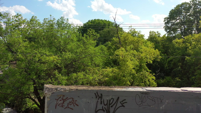 Aerial shot of vehicles on street in city by lake against sky, drone ascending over structures on sunny day - Lake Geneva, Wisconsin