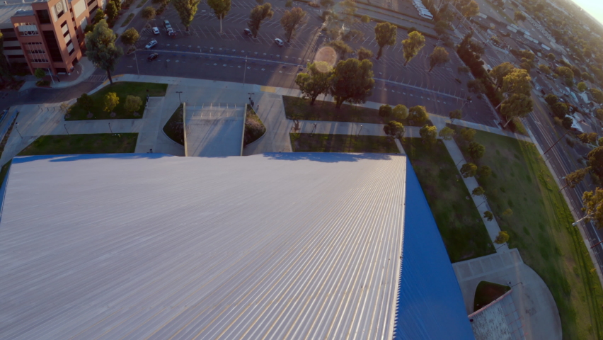 Aerial moving down and around the side of the Walter Pyramid at Long Beach State University under a bright sunny blue sky with shadows and the distant city along the horizon