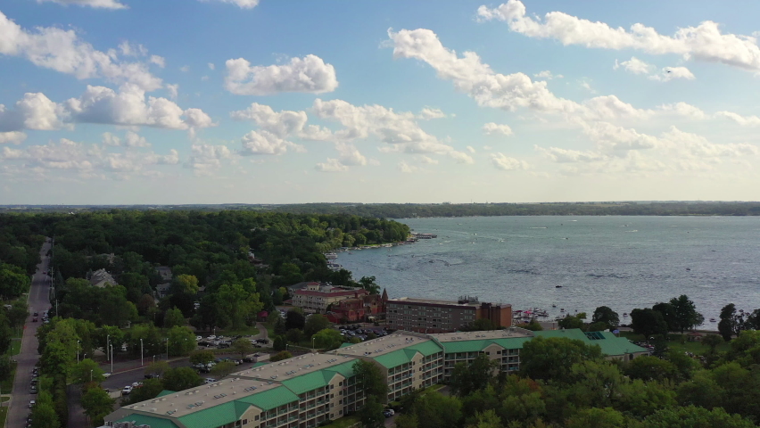 Aerial panning shot of buildings and vehicles in city by lake, drone flying over structures against sky - Lake Geneva, Wisconsin