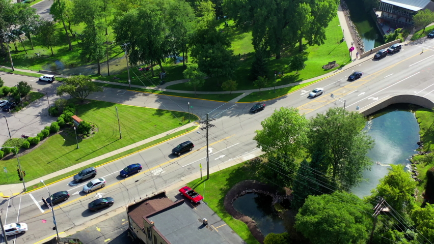 Aerial tilt up shot of vehicles on street in city by lake against sky, drone flying over structures on sunny day - Lake Geneva, Wisconsin