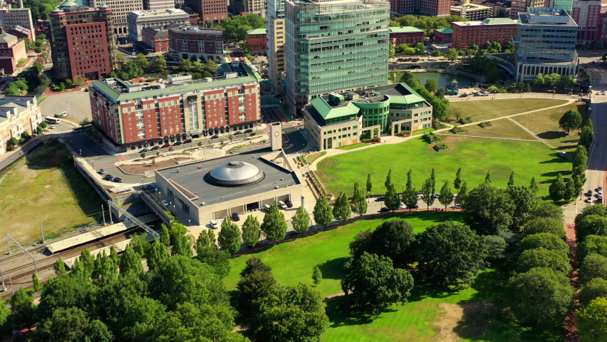 Aerial shot of trees and buildings by state government office, drone flying backward over city on sunny day - Providence, Rhode Island