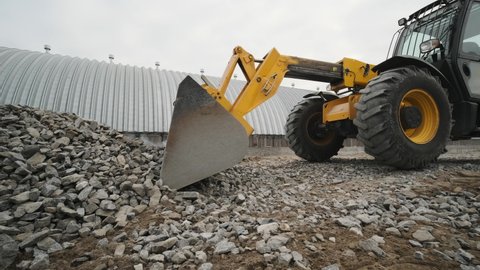 Tractor moves rubble to truck. Excavator-loader rakes rubble from pile at construction site and loads dump truck. Clearing site