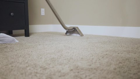 Worker cleaning carpet using professional-grade equipment for steam cleaning hot water extraction of carpet fibers. In bedroom or residential office. Mid to close up push shot, 50% speed.