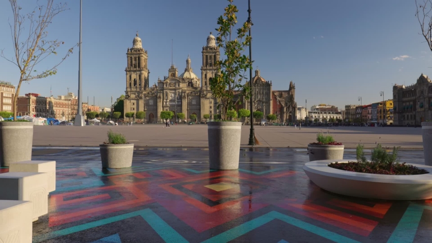 Central square and the cathedral in Mexico City. Camera moves between flowerpots with plants and looks out onto square with the magnificent cathedral. Mexico City, CDMX, Mexico