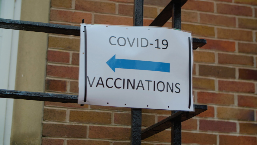 Covid-19 Vaccination signs to Vaccination clinic this way with blue arrow. Homemade signage found in the UK suburbs, DIY notice tells public which way to go for help during the coronavirus pandemic  | Shutterstock HD Video #1068523874