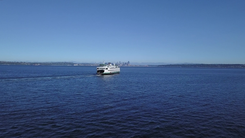 Aerial follow of the Seattle Ferry and downtown Seattle Washington city skyline in the distance.