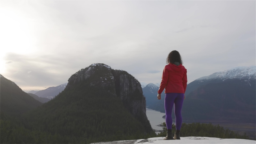 Adventurous and Excited Girl Hiking in the mountains during a sunny Winter Sunset. Taken in Squamish, North of Vancouver, British Columbia, Canada. Concept: Adventure, freedom, lifestyle, health