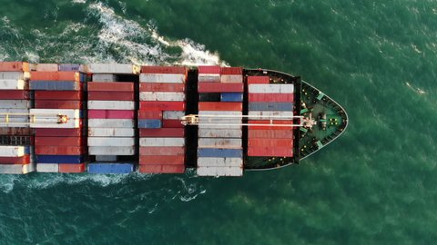 Aerial top view of smart cargo ship carrying container and running very fast for export cargo from container yard port to custom ,Contrail line in the ocean by large ship very fast. 