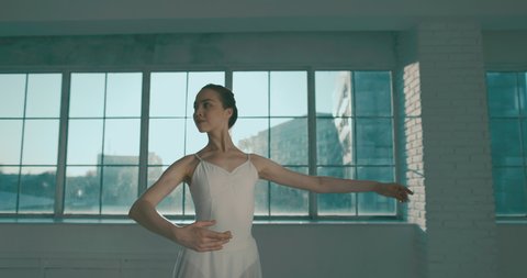 Slender attractive caucasian girl dancing ballet. Young talented choreographer preparing her stage performance, spinning around herself in studio 4k footage