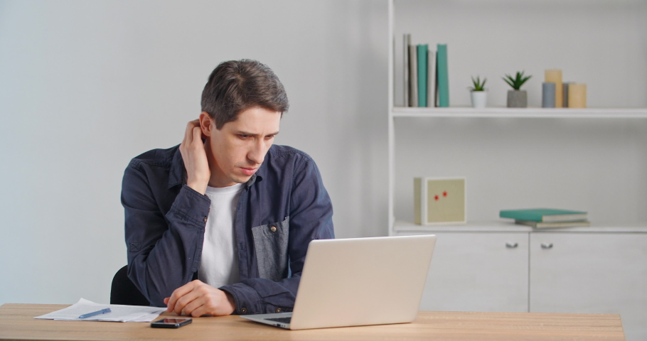 Thoughtful freelancer millennial guy business man thinking of online service problem in laptop. Serious doubtful male sitting at home office desk considering financial risks making difficult decision Royalty-Free Stock Footage #1068531992
