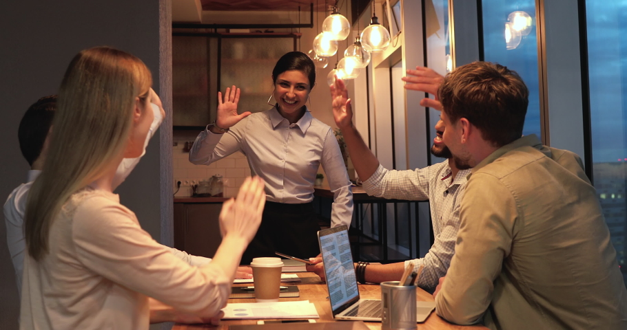 Happy attractive indian mixed race female leader giving high five to smiling young diverse coworkers, celebrating achieving goal or finishing brainstorming meeting, team building motivation concept. Royalty-Free Stock Footage #1068540929