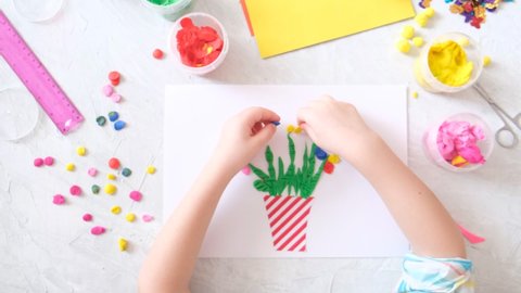 Child making homemade greeting card. little girl making vase with flowers from paper and clay, plasticine as gift for Mothers day, Birthday or Valentines day . Arts  crafts concept.