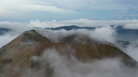 Close up aerial view of the top of the mountain ridge on active volcano mount Batur surrounded by fog