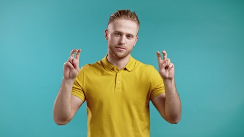 Handsome man showing with hands and two fingers air quotes gesture, bend fingers isolated over blue background. Not funny, irony and sarcasm concept.