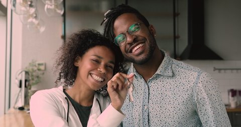 Happy young bonding african american family couple looking at camera, showing keys form new apartment, feeling excited or purchasing own house or moving into rental dwelling, real estate concept.