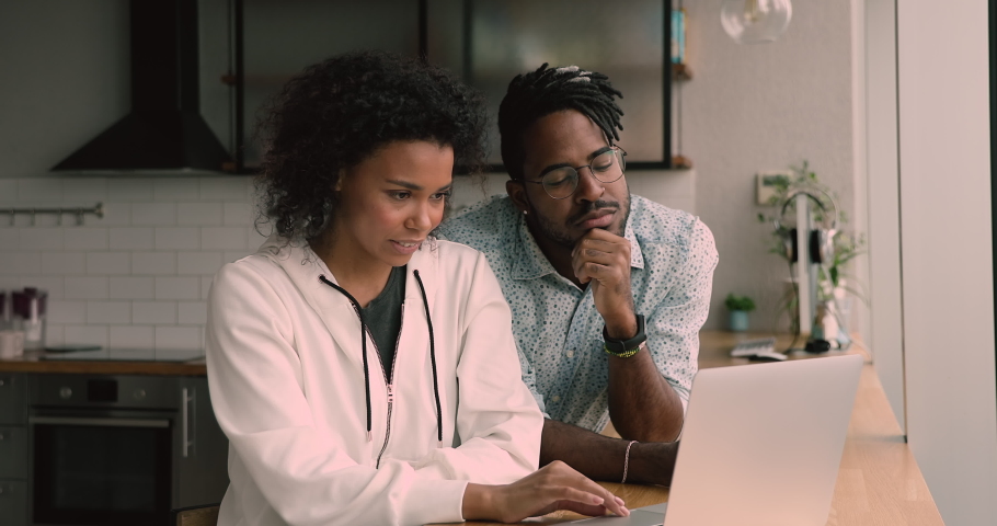 Happy young african mixed race family couple looking at computer screen, amazed by reading email with good news, finding good sale profitable shopping deal, feeling excited giving high five at home. Royalty-Free Stock Footage #1068548057