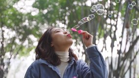 4k slow motion low angle view close up of one Beautiful young Asian girl blowing bubbles in the bamboo forest pretty woman enjoy spring sunshine relax in the nature - Powered by Shutterstock - Get 15% off with code: PIKWIZARD15