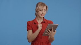 Young woman using digital tablet, blue background. Young woman browses the Internet on tablet computer. Online shopping concept.Slow motion video.