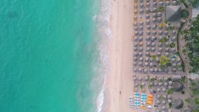 Aerial view on tropical island and exotic beach reasort. Umbrellas, sand and sea waves, 4k video