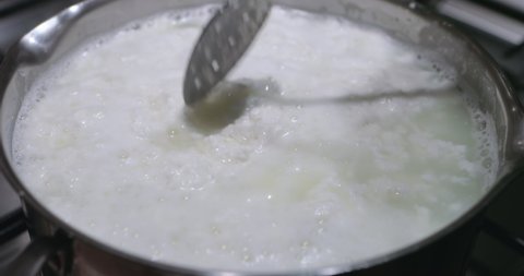 Home made cottage cheese or curd cheese. Pan with milk stands on the kitchen stove. Manufacture of cheese and desserts at home and restaurant or cafe. Cooking healthy food at home. Fermented food.
