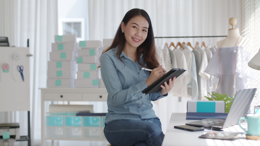 Portrait young attractive asia female owner startup business look at camera work happy with box at home prepare parcel delivery in sme supply chain, procurement, omnichannel commerce online concept. | Shutterstock HD Video #1068555368