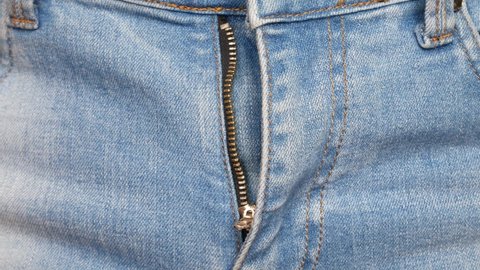 Close-up of man's hands fastening a clasp on his jeans and the button