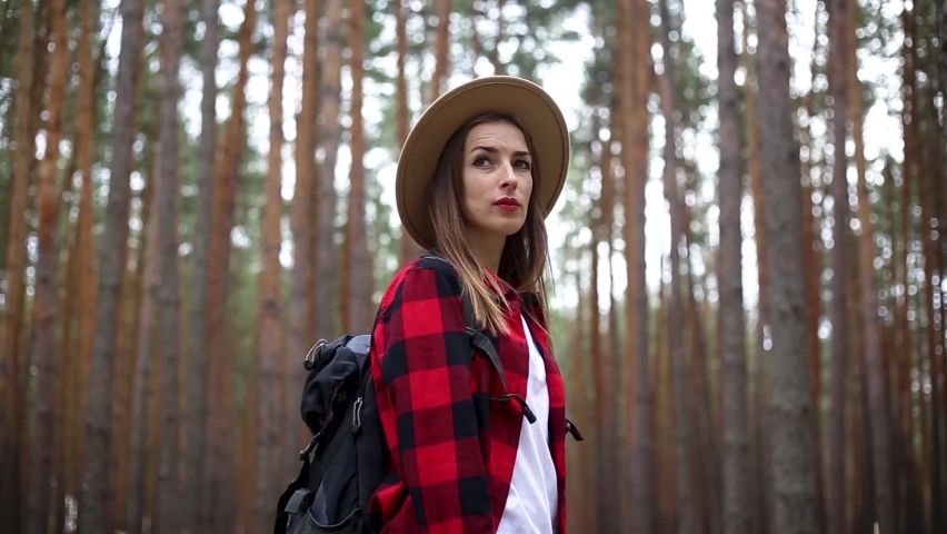 Woman in a hat with a hiking backpack in the forest. Concept hike, tourism.