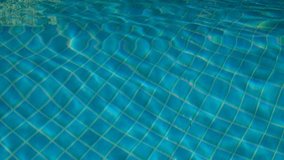 Close up of a pool water surface with small shiny ripples in a sunny day.Natural light.Blue water.Water reflecting.Abstract pool water surface and background with sun light reflection.video.