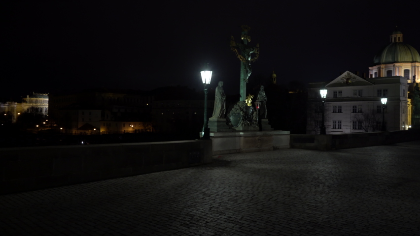 crossing of a street lighting lamp and an illuminated sculpture of St. Crosses with Calvary from the 18th century on a stone tower on Charles Bridge over the Vltava River in the center of Prague  Royalty-Free Stock Footage #1068561299