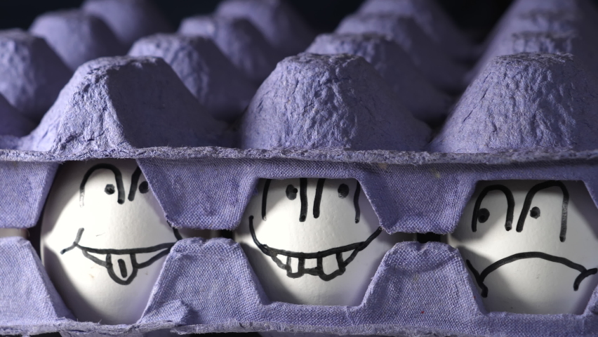 Two blue egg trays with the drawn faces eggs on the center