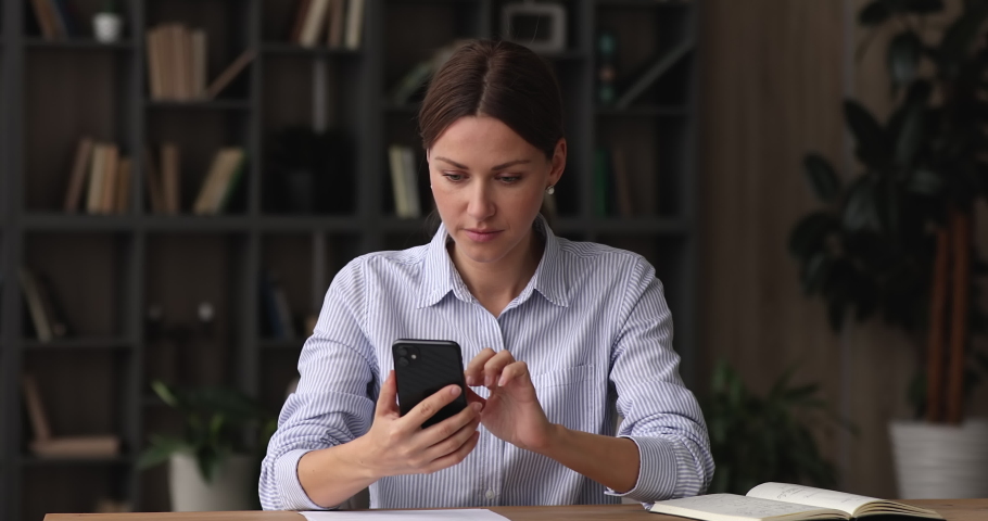 Unhappy anxious young business lady using smartphone, feeling dissatisfied with data loss, poor internet connection, bad device or software app work, getting scam phishing message or bad news email. Royalty-Free Stock Footage #1068565856