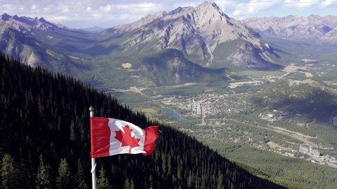National Flag of Canada with Town of Banff in background. Cascade Mountain and surrounding Canadian Rocky Mountains in summer time. Banff National Park, Alberta, Canada.