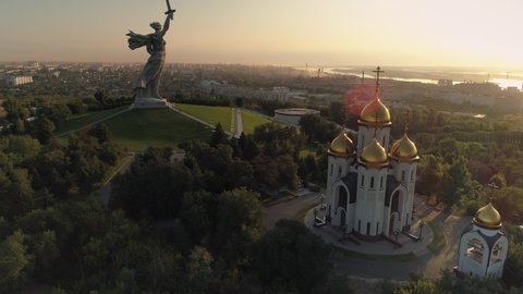 Volgograd, Russia - 18 june 2020 year: Motherland church, mother calls statue, sculpture memorial complex mound at cinematic orange sunset. Best cityscape. Picturesque downtown. Romantic clouds. Stock