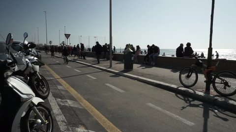 Ostia, Rome, Italy - February 28, 2021, people walking, running and cycling on the waterfront on a beautiful sunny day.