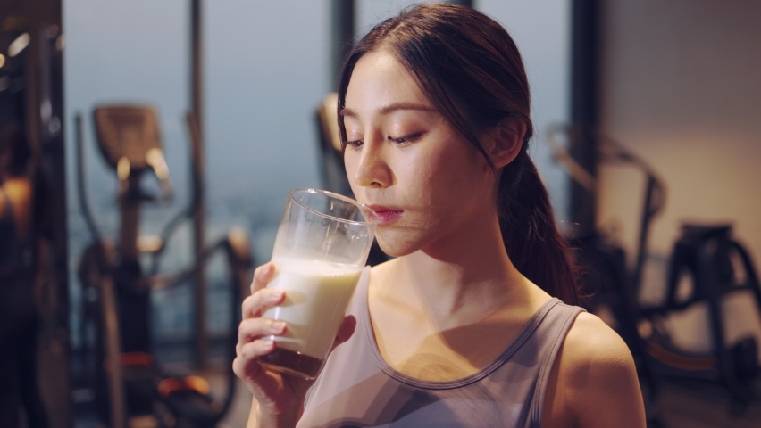 Attractive fitness asian woman finishing workout and drinking protein milk shake vitamins after training. Bodybuilding. Healthy lifestyle. | Shutterstock HD Video #1068580478