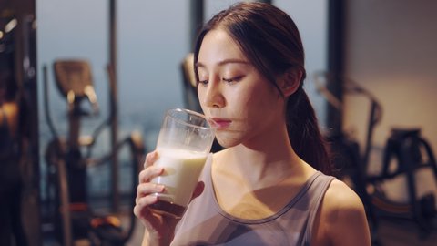 Attractive fitness asian woman finishing workout and drinking protein milk shake vitamins after training. Bodybuilding. Healthy lifestyle.