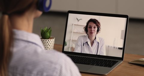 Smiling trusted young female doctor general practitioner consulting patient distantly by computer video call, discussing healthcare or illness treatment, telemedicine web camera communication.