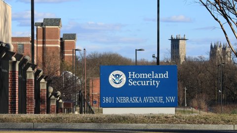 Washington, DC - USA - March 6 2021: A sign at an entrance to the U.S. Department of Homeland Security headquarters on Nebraska Avenue. Vehicle traffic is seen in the foreground. Cathedral is visible.