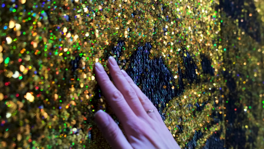Sparkling glitter background, sequins texture bokeh with iridescent luster. Concept. Female hand touching shining golden fabric. Royalty-Free Stock Footage #1068586298