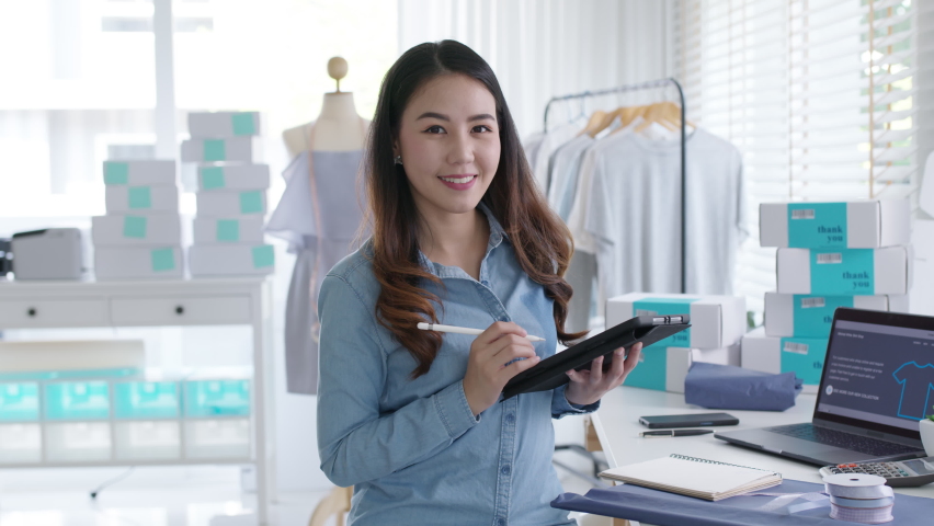 Portrait young attractive asia female owner startup business look at camera work happy with box at home prepare parcel delivery in sme supply chain, procurement, omnichannel commerce online concept. | Shutterstock HD Video #1068587162