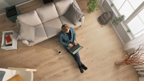 businesswoman sitting on floor works from home using computer top down view overhead,young business woman freelance working remote typing on laptop above shot indoors,distance work concept