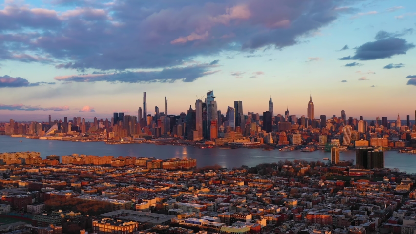 Urban Skyline of Midtown Manhattan, Jersey City and Hudson River at Sunset. Sunlight on Buildings. New York City, USA. Aerial View. Drone Flies Sideways Royalty-Free Stock Footage #1068598040