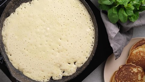Frying thin crepe on a pan. Blini, french crepes cooking process, top view