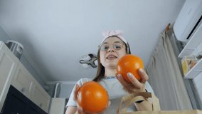 Smiling woman juggles fruits in the kitchen. Funny positive video.Slow motion