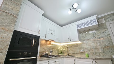 Ultra wide angle closeup up to down tilt camera movement of modern classic white kitchen interior with furniture and appliances