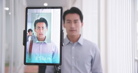 facial recognition concept - Asian businessman using face scanner to clock in work and check body temperature