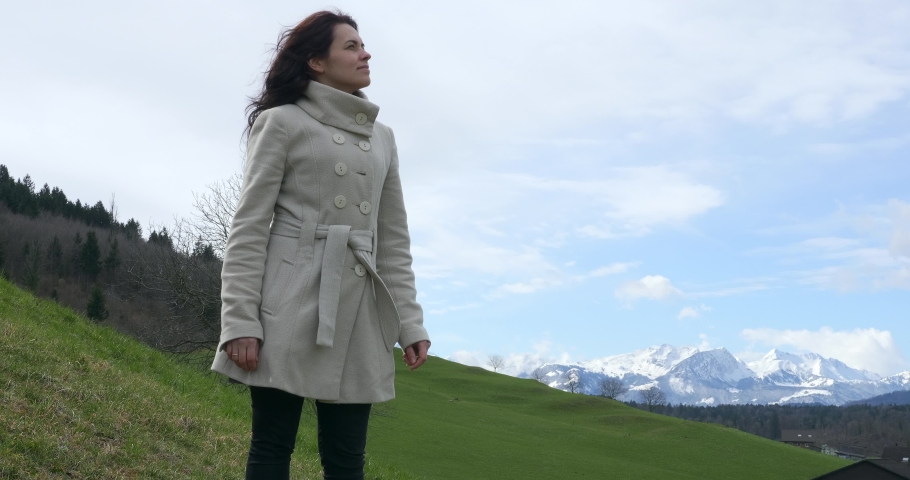 Woman Enjoys Fresh Air and Watching at Scenic Mountains. Tourist Travel in Picturesque Swiss Alps. Green Grass Pastures Meadows. Cottages in Village. Switzerland Europe