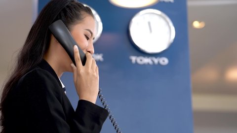 Asian concierge woman welcoming someone at lobby counter for airport or hotel check in. staff receptionist smiling and talking. Concept operation of hospitality for service and tourism.